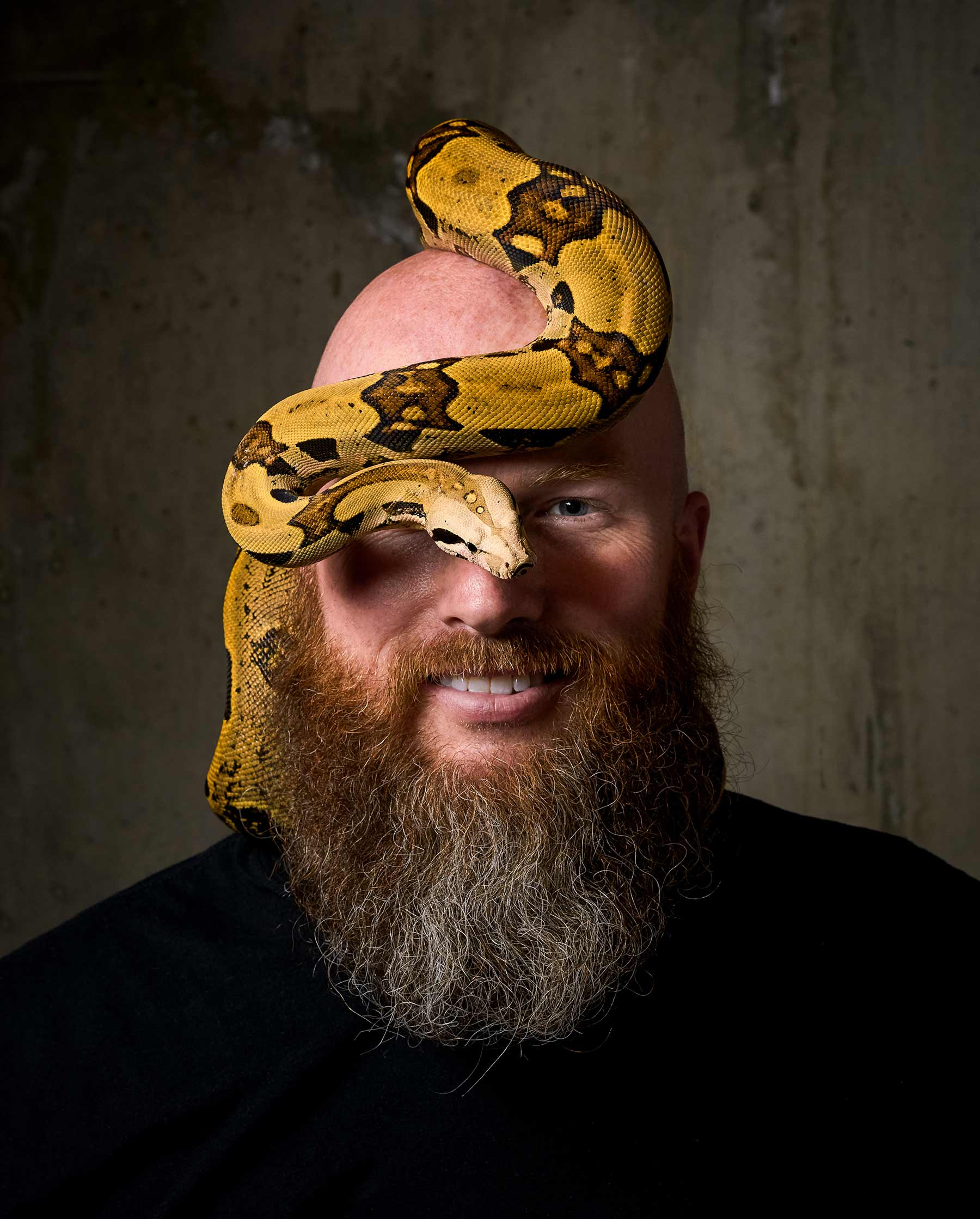 A-studio-portrait-of-a-man-with-a-yellow-and-black-snake-on-his-head