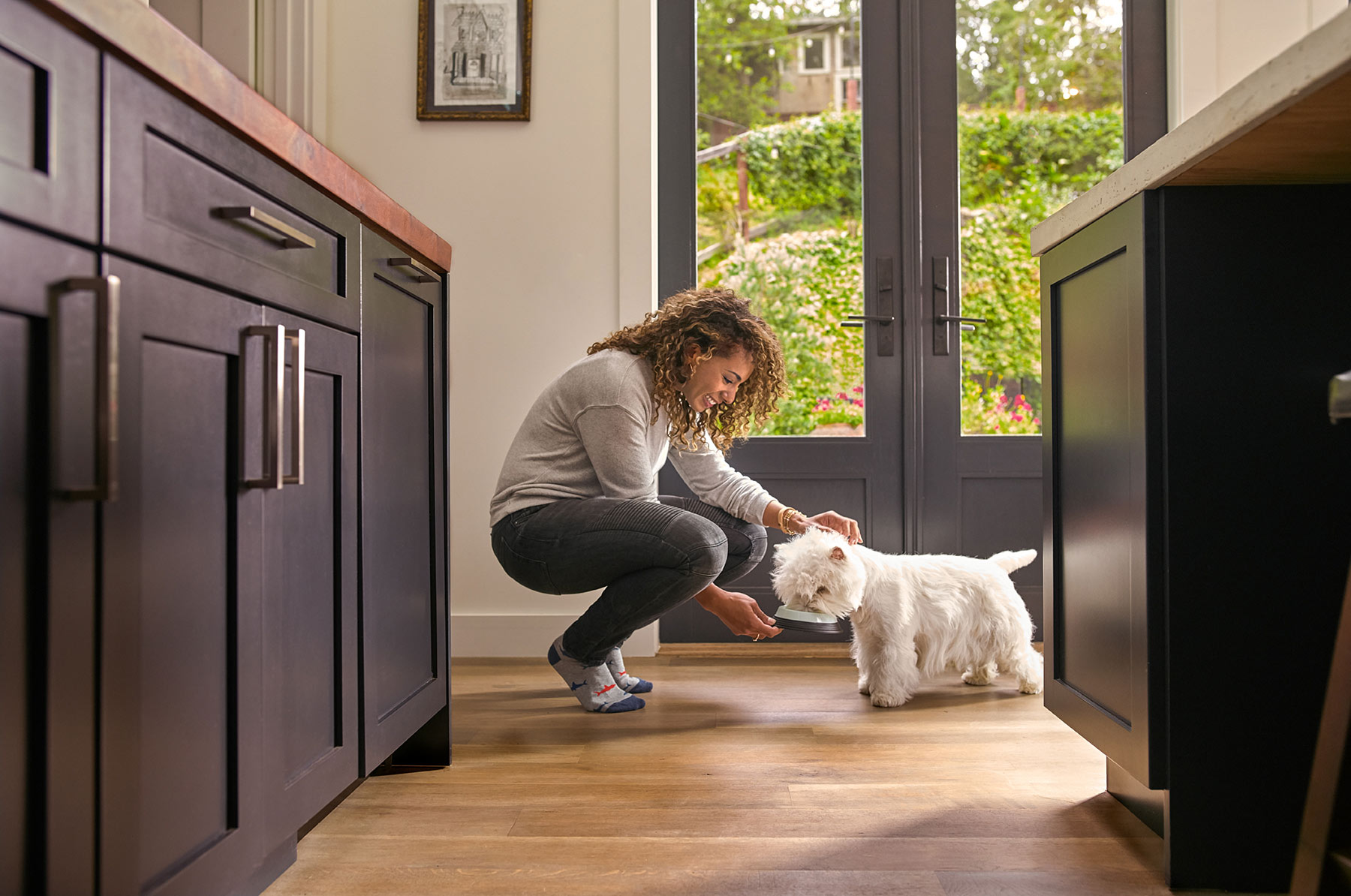 A-woman-feeding-her-dog-in-the-kitchen