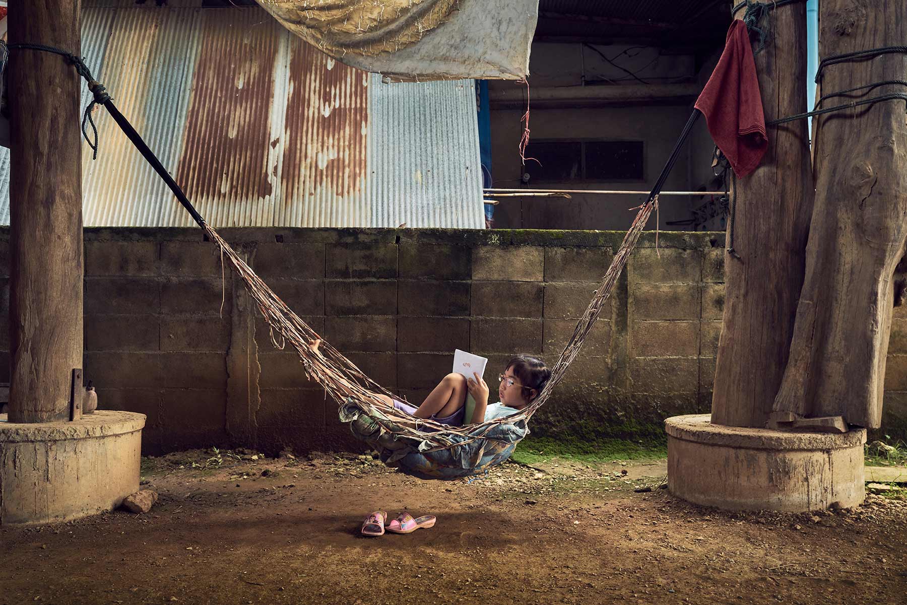 A-portrait-of-a-young-boy-relaxing-on-a-hammock-in-a-large-room-with-dirt-floors