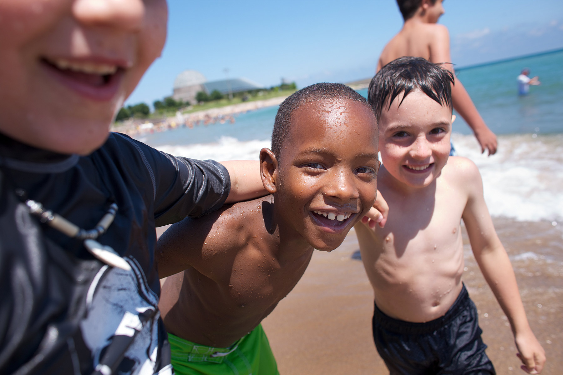 Four-little-boys-playing-on-a-beach-near-the-edge-of-the-ocean